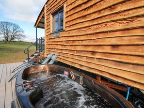 A wooden cabin with a hot tub and outdoor seating. - Wild Acre (Llangadog)