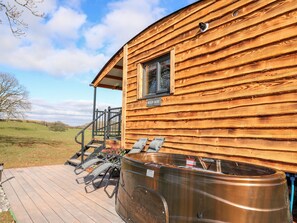 A wooden cabin with a hot tub and outdoor seating. - Wild Acre (Llangadog)