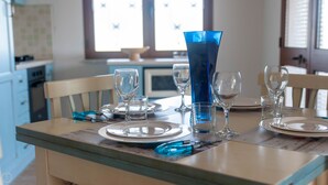 Una mesa de comedor dispuesta con platos, vasos y un jarrón azul.