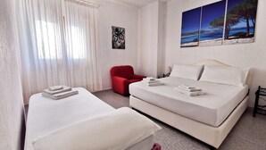 A hotel room with a bed, a red armchair, and a painting of a beach scene. - La Casa Di Rita - Salamaghe (Muriscuvò)