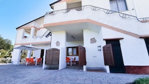 A two-story building with a covered outdoor seating area, a staircase, and a door with shutters. - La Casa Di Rita - Salamaghe (Muriscuvò)