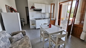 A compact kitchen with white cabinets, a dining table with two chairs, and a refrigerator. - La Casa Di Rita - B - Lu Nibbaru (Muriscuvò)