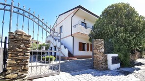 A two-story house with a stone gate, a stone pillar, and a well-maintained garden. - La Casa Di Rita - B - Lu Nibbaru (Muriscuvò)
