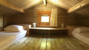 A cozy attic bedroom with wooden walls and a sloped ceiling.