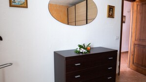A room with a dark wooden dresser, a round mirror, and a small table with a flower arrangement. - L'Alzoni - Two Bedroom House, Sleeps 5 (L'alzoni)