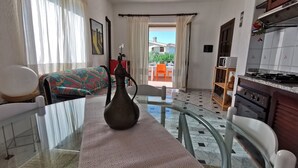 A hotel room with a bed, a dining table, a kitchen area, and a view of the outside.