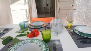 A dining table set with plates, glasses, and a vase of flowers.