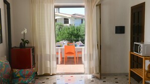 A room with a dining area, a microwave, and a view of a building and trees outside.