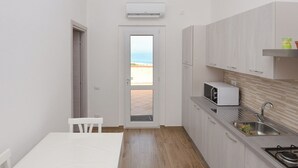 A compact kitchen with a view to the outside, a microwave, a sink, and a small table. - Villa Paola - Panoramic Seaview Terrace (Costa Rei)