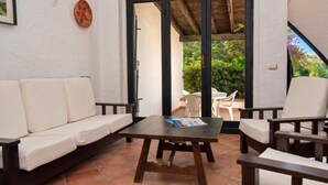 A patio with a sofa, chairs, and a table. - Villa Adele | Garden & BBQ near the beach (Costa Rei)