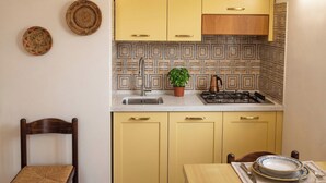 A kitchen with yellow cabinets, a sink, a stove, and a chair.