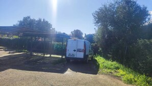 A white van parked on a gravel path with a metal structure in the background. - Villa Giorgia with garden - 50m from the Beach (Costa Rei)