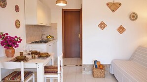 A compact living space with a dining area, kitchenette, and a sofa. - Villa Oleandro with garden & BBQ - near the beach (Costa Rei)