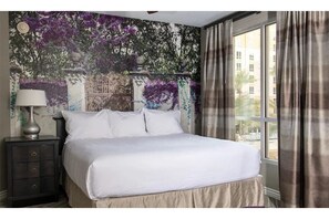 Relax in a spacious room with a large bed, nightstand, and window offering a view of the outside.