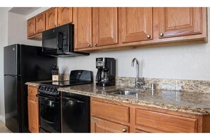Compact kitchen with a classic design, featuring a refrigerator, microwave, coffee maker, and toaster.