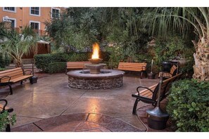 Relax by the central fire feature surrounded by lush greenery and comfortable benches.