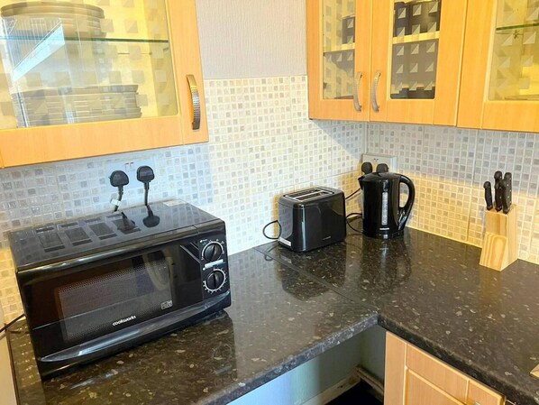 A kitchen with a black microwave, a toaster, and a coffee maker on the counter. - Remarkable 2-bed Apartment in London (London)