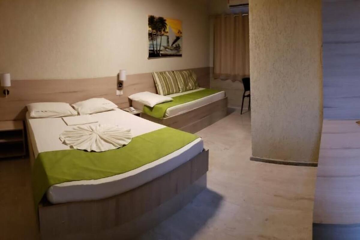 A hotel room with two beds, a TV, and a painting on the wall.