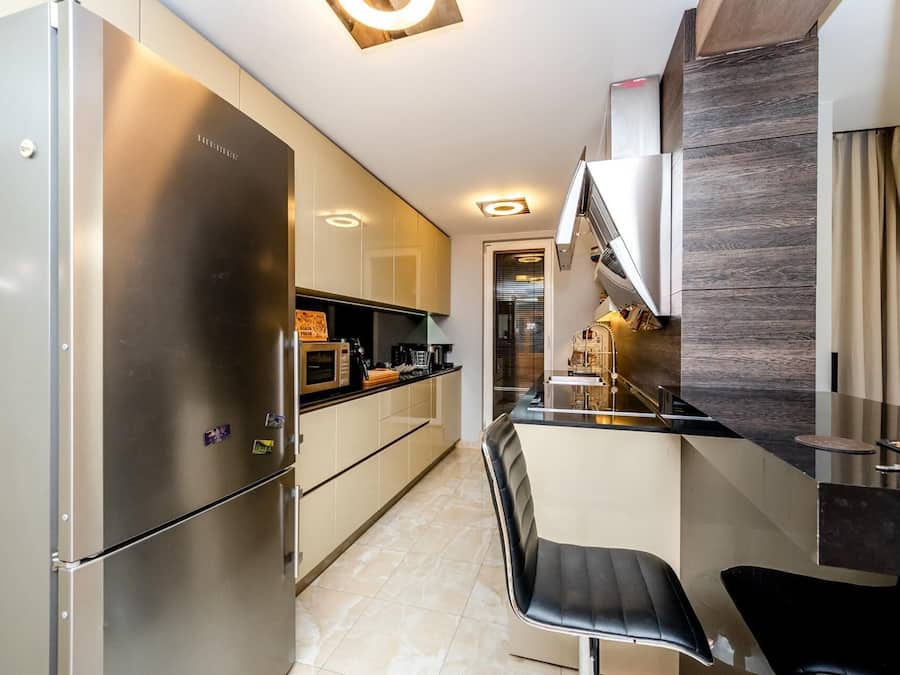 A modern kitchen with stainless steel appliances, a black bar counter, and a seating area with a chair.
