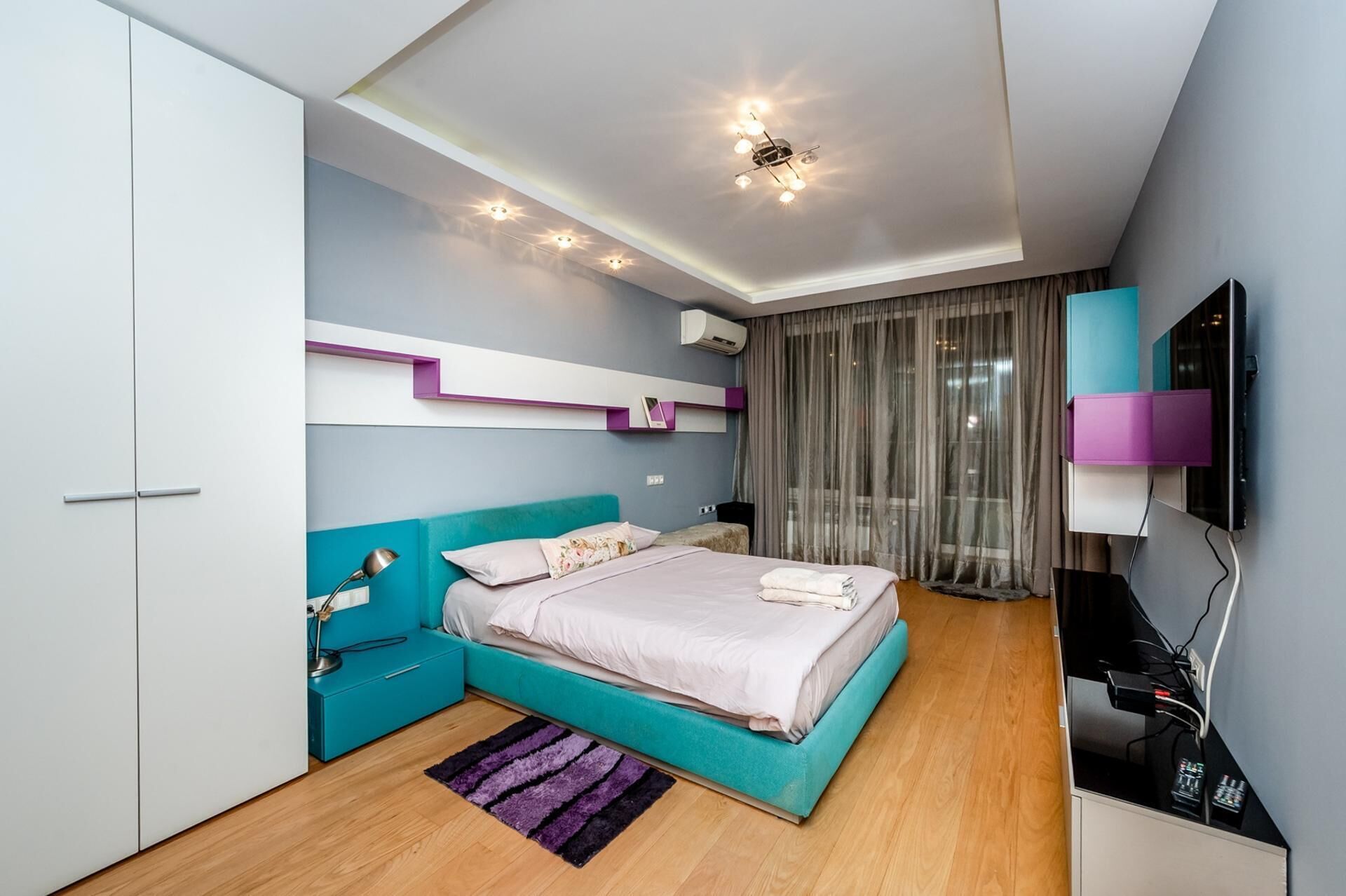 Une chambre moderne avec un lit, un bureau, une télévision et une armoire.