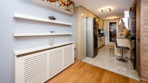 Cocina moderna con refrigerador integrado, comedor con taburete de bar y pasillo que conduce a un baño.
