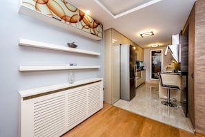 Une cuisine moderne dotée d’un réfrigérateur encastré, un coin repas avec un tabouret de bar et un couloir menant à une salle de bain.