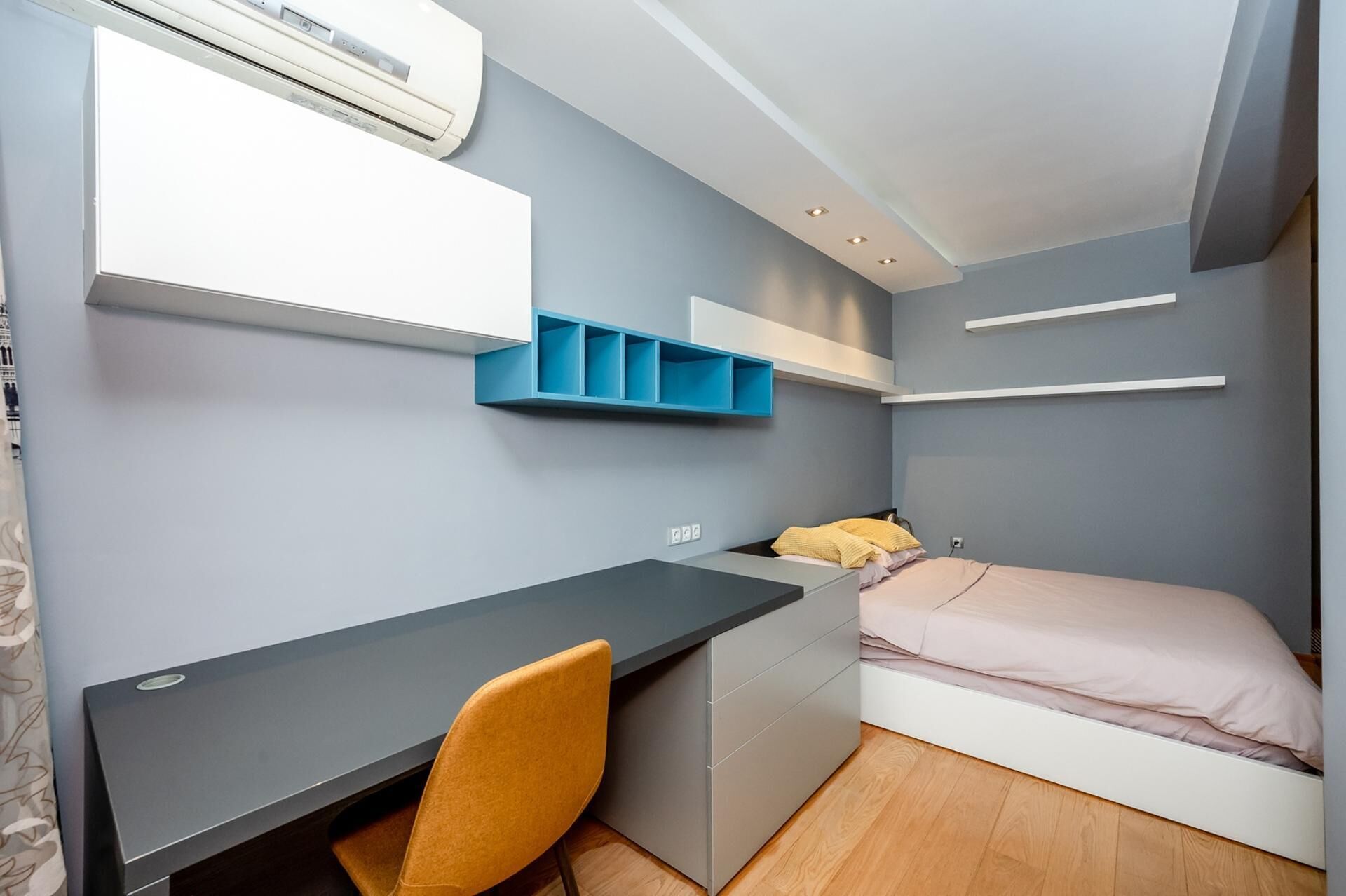 A compact bedroom with a bed, a desk, and a chair.