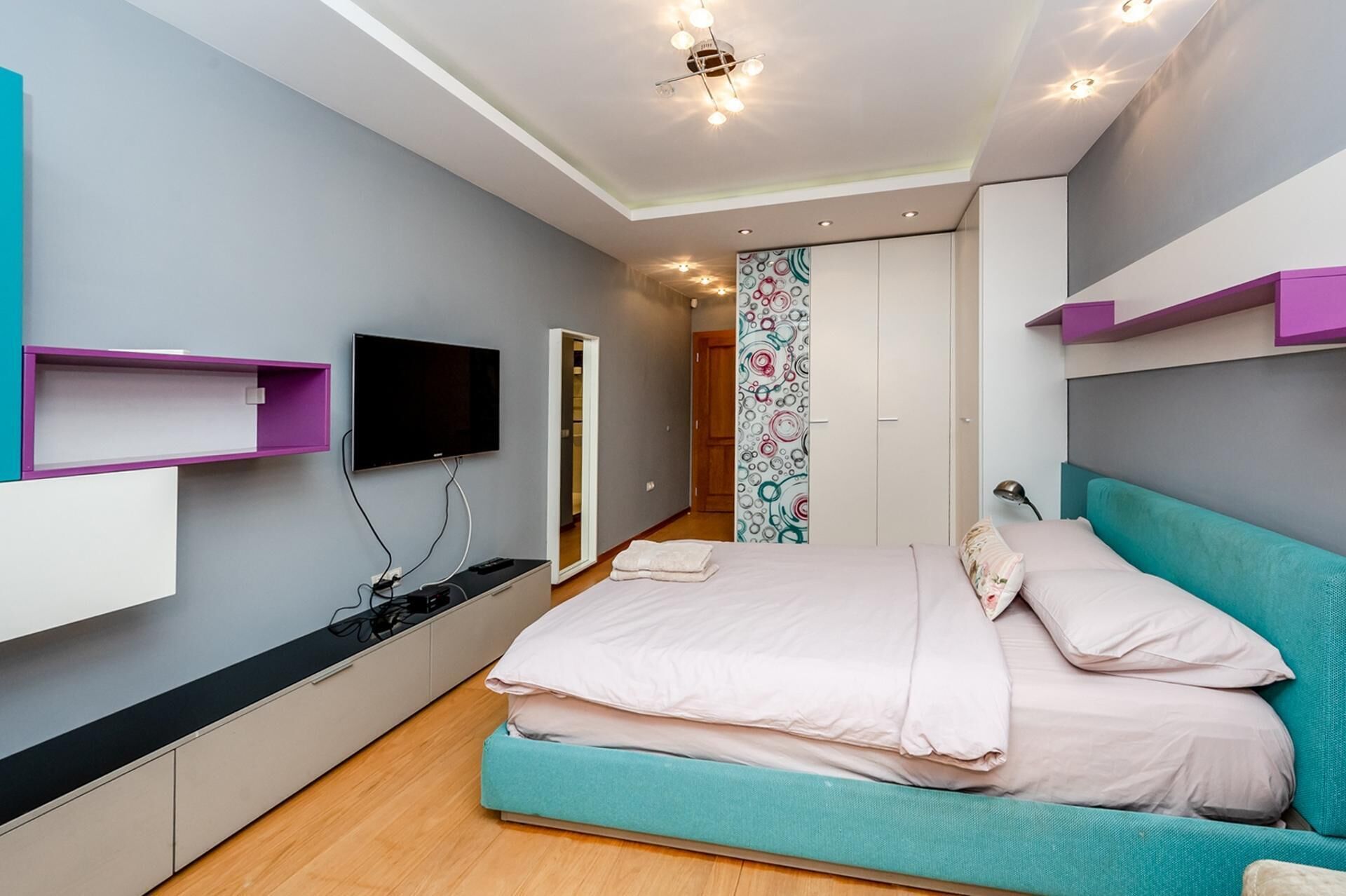 A modern bedroom with a bed, a TV, and built-in storage.