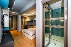 A modern hotel room with a bed, a desk, a shower area, and a view of the city. - Sofia Luxury 3-bed Penthouse Apartment, Sleeps 6 (Sofia)