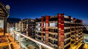 Un edificio de varios pisos con balcones, barandilla de vidrio y vista de la calle.