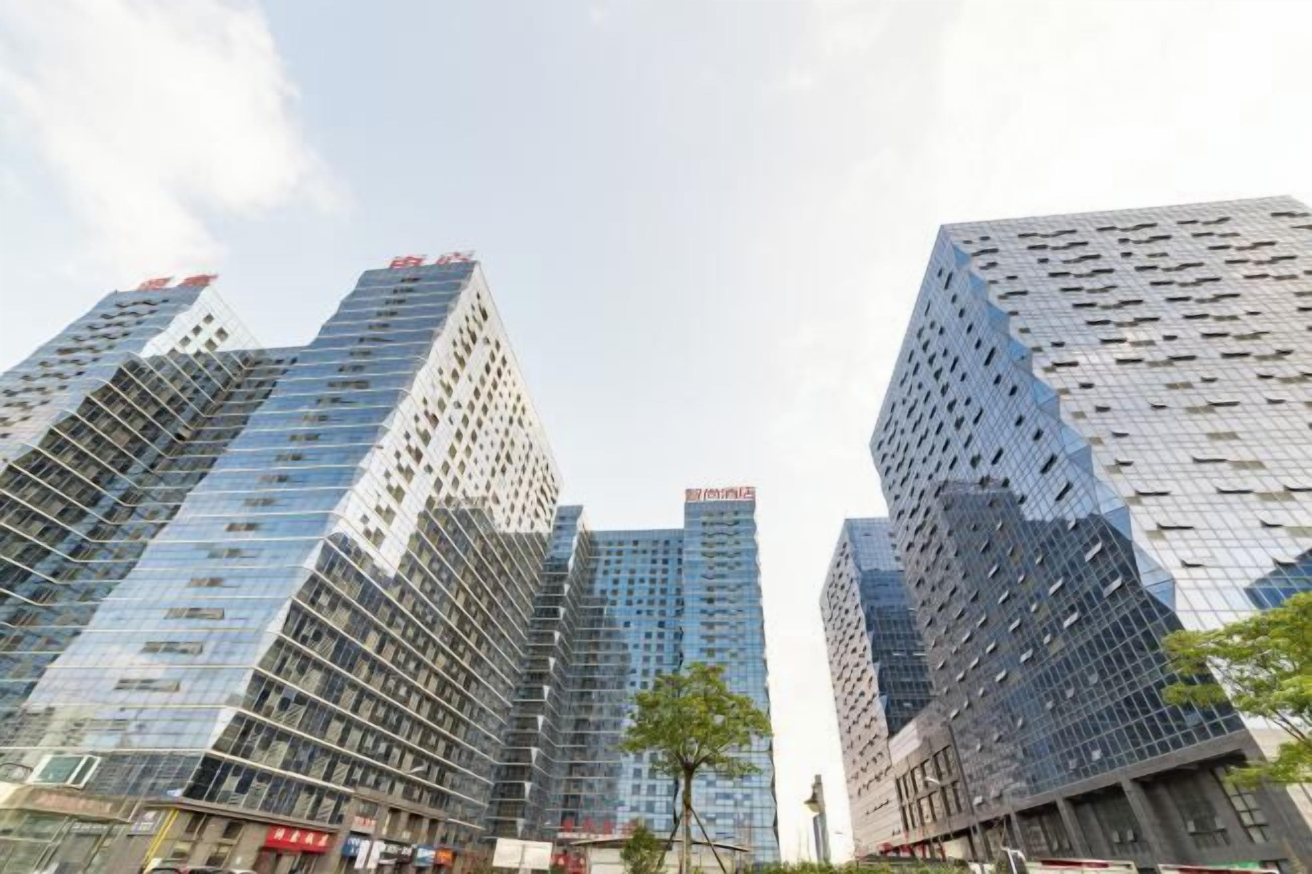 A cluster of high-rise buildings with reflective glass facades and a clear sky.