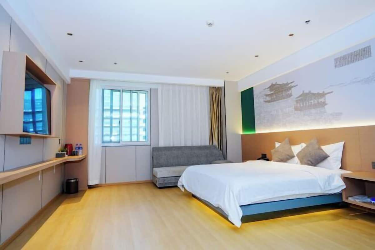 Ein modernes Hotelzimmer mit Bett, Fernseher, einem Fenster mit Vorhängen und einer Wand mit traditionellem Design.