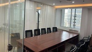 A conference room with a long wooden table and black chairs, large windows with curtains, and a projector mounted on the ceiling. - ELONG ruiyun Hotel (Yancheng International Exhibition Center) (Yancheng)