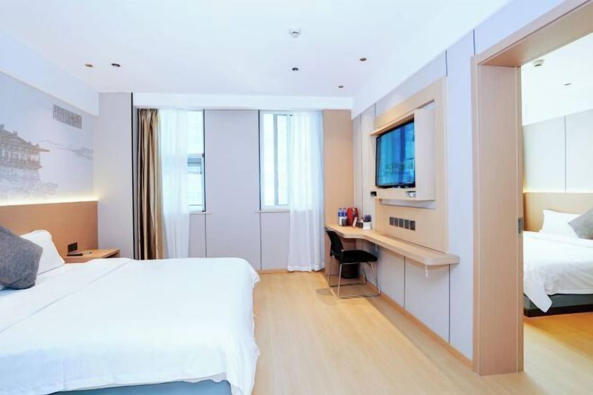 Ein modernes Hotelzimmer mit einem großen Bett, einem Schreibtisch, einem Fernseher und einem Schiebetürenschrank.