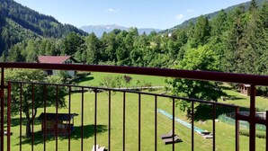 Un balcón con vistas a un paisaje verde, una estructura de madera y una valla metálica.