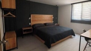 A modern bedroom with a bed, bedside tables, a wooden wardrobe, and a window with blinds.