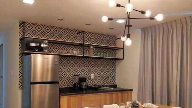 A modern kitchen with a built-in refrigerator, a dining table set for four, and a pendant light fixture.