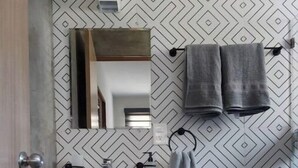 Ein modernes Badezimmer mit einem Holzlagerflansch, einem weißen Waschbecken, einer Toilette und einem Spiegel über dem Waschbecken.