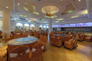 A banquet hall with round tables and chairs, large windows, and a chandelier. - Vienna Hotel ( Hunan Zhangjiajie City Park ) (Zhangjiajie)