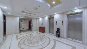 A hotel lobby with a marble floor, elevators, and a reception area. - Vienna Hotel ( Hunan Zhangjiajie City Park ) (Zhangjiajie)