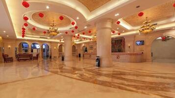 A spacious lobby with a marble floor, a reception desk, and a chandelier.