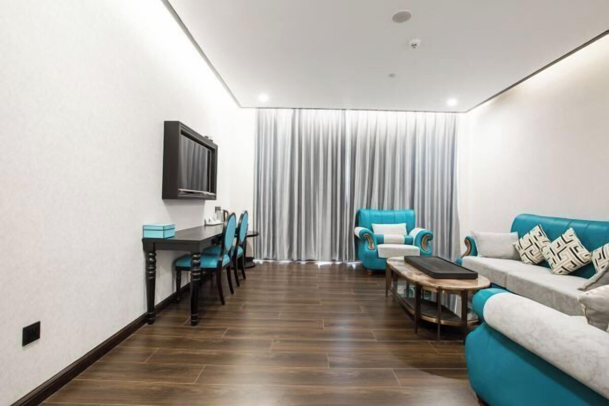 A modern living room with a dining area, a sofa set, and a TV mounted on the wall.