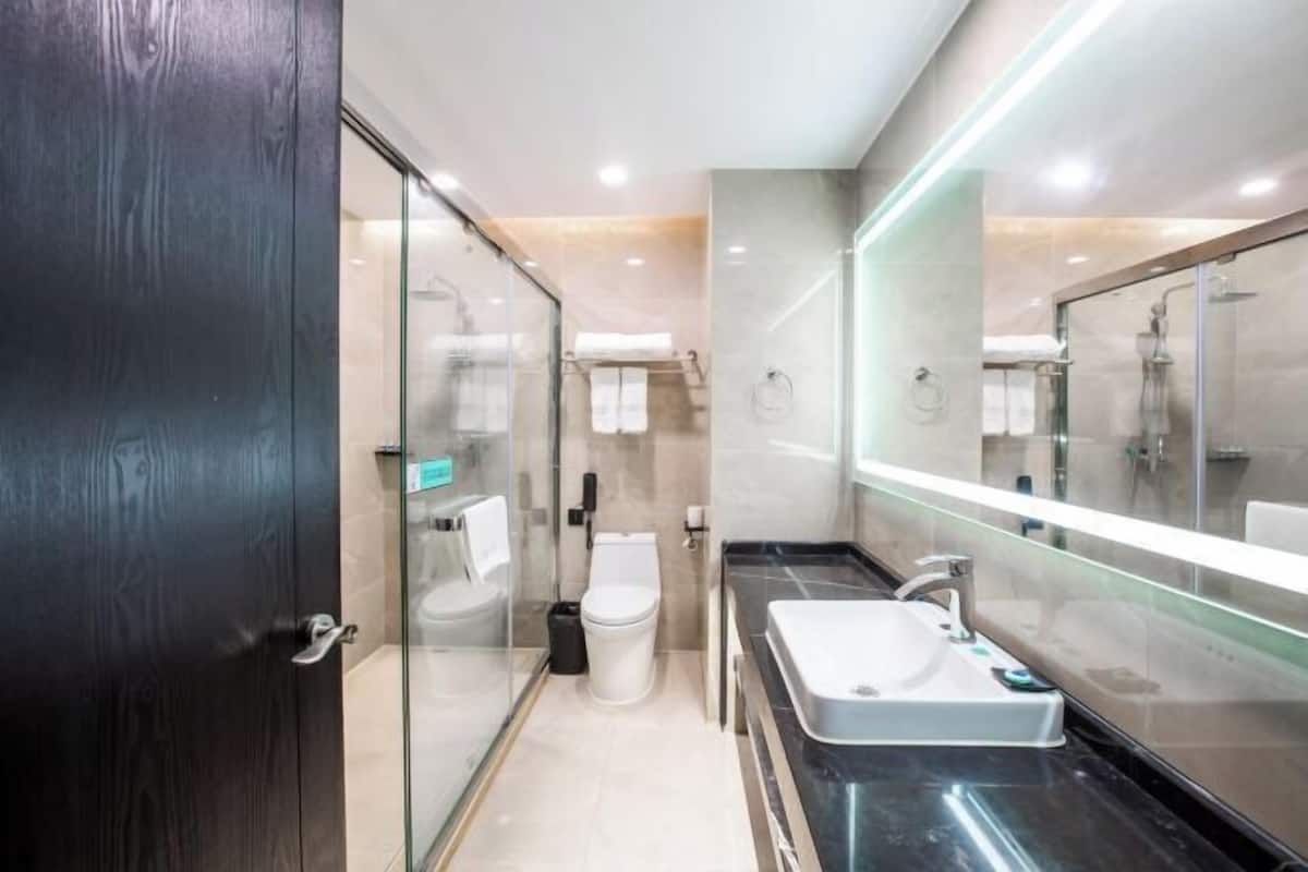 A modern bathroom with a glass shower enclosure, a large mirror, and a black countertop sink.