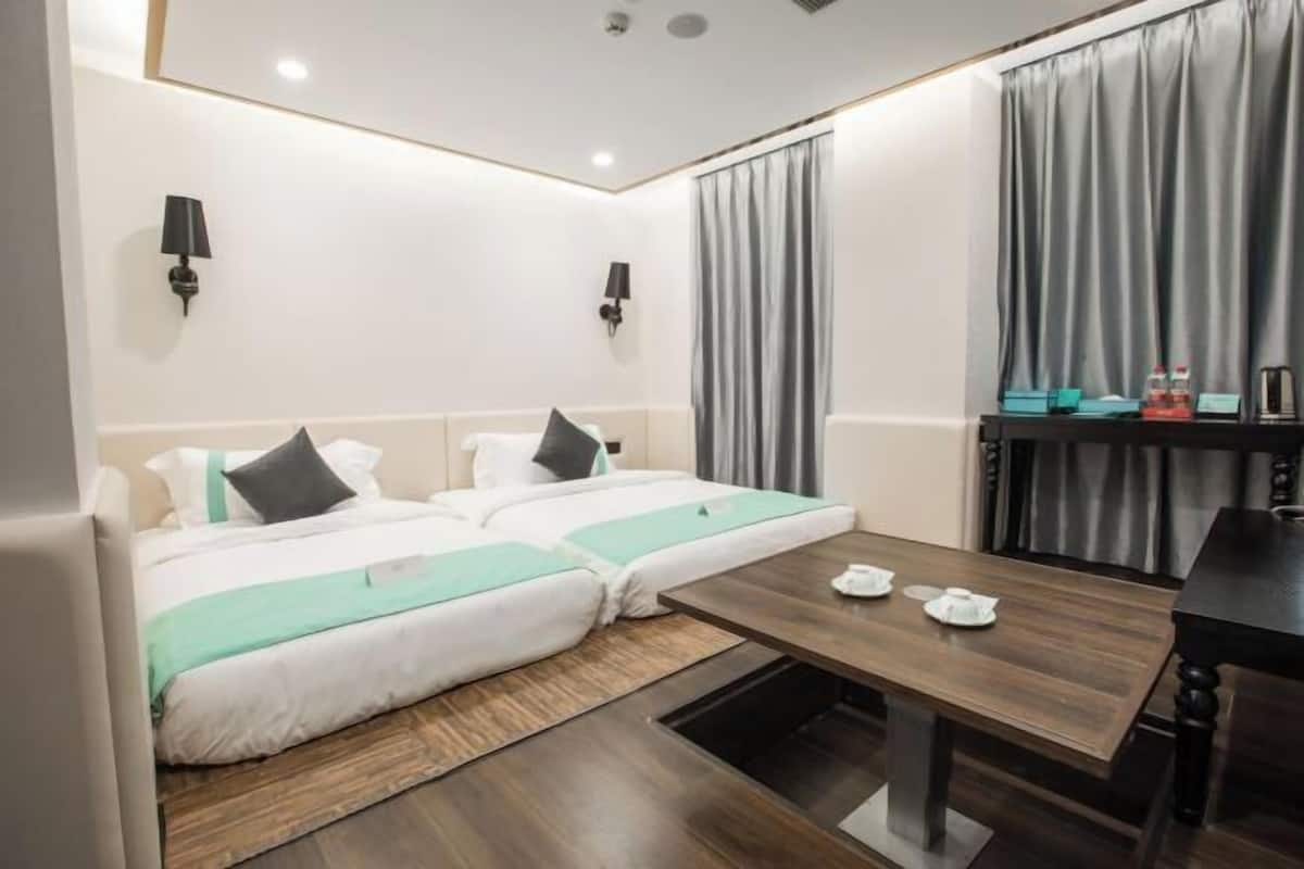 A hotel room with two beds, a wooden table, and a small dining area.