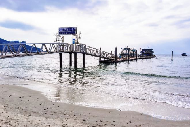 A pier extending into calm water with a clear sky above.