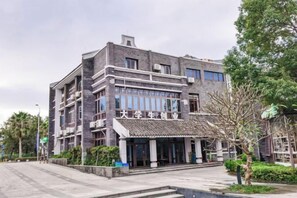 A multi-story building with a traditional architectural style, featuring a prominent entrance with a tiled roof and a sign above the entrance. - Xi . Hotel (Huidong)