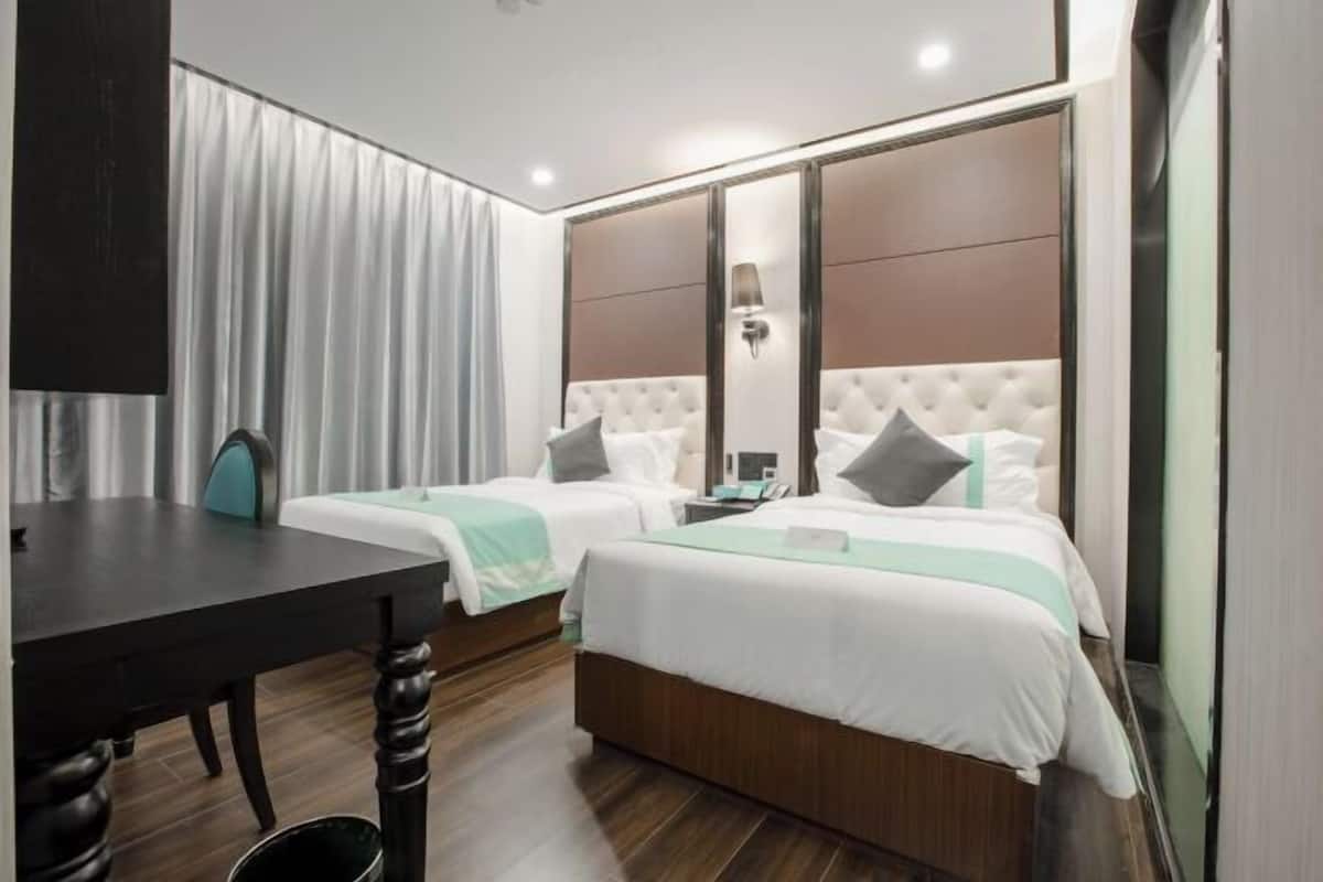 A hotel room with two beds, a desk, and a large mirror.