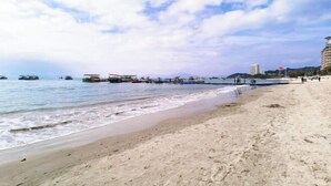 A beach with a sandy shore, boats, and a pier.