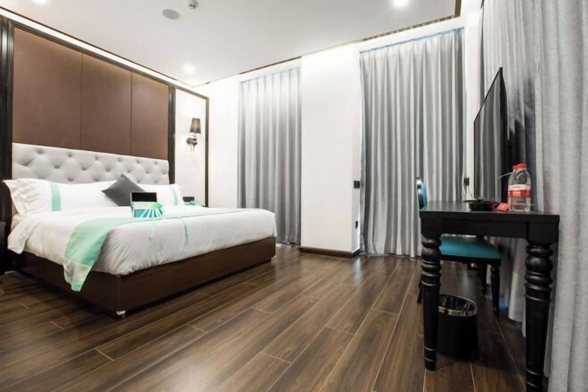 A modern hotel room with a large bed, a desk, and a television.