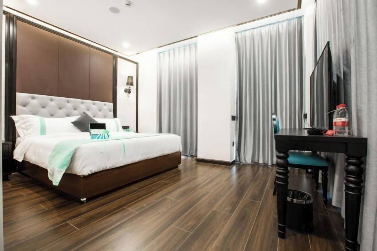 A modern hotel room with a large bed, a desk, and a TV.